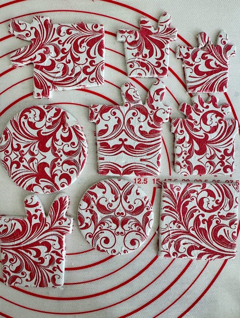 Red and white patterned cookies are shaped like gingerbread people and circles, arranged on a baking mat with circular measurements.