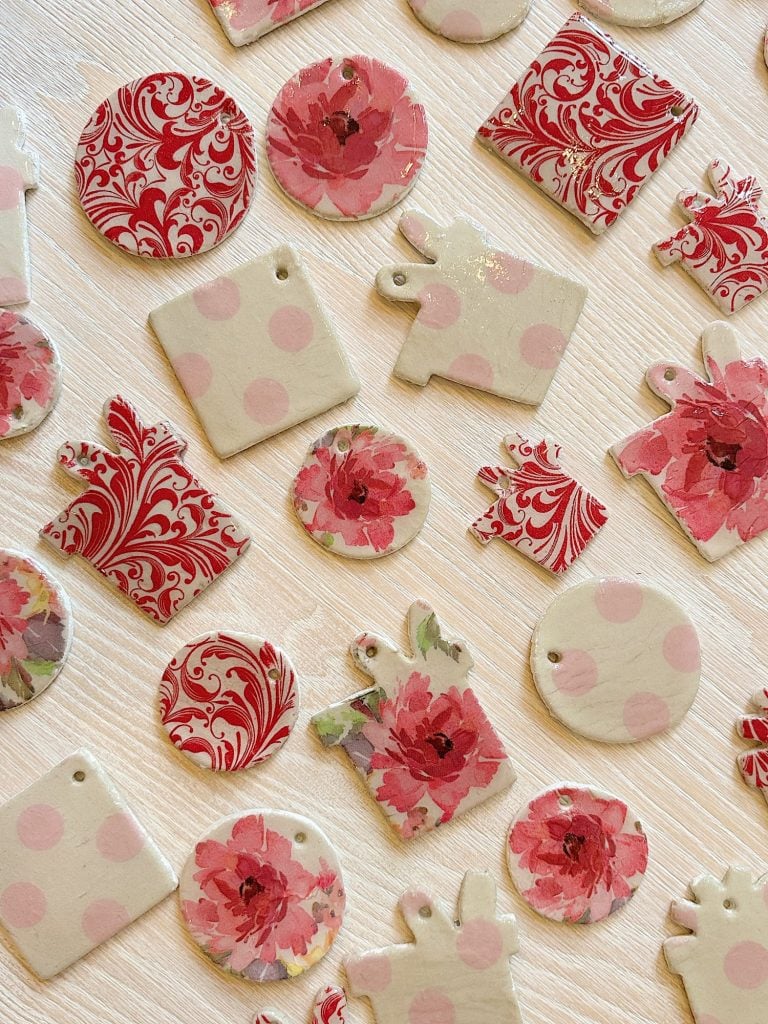 Various shaped ceramic pieces with pink floral and red swirl patterns on a wooden surface.