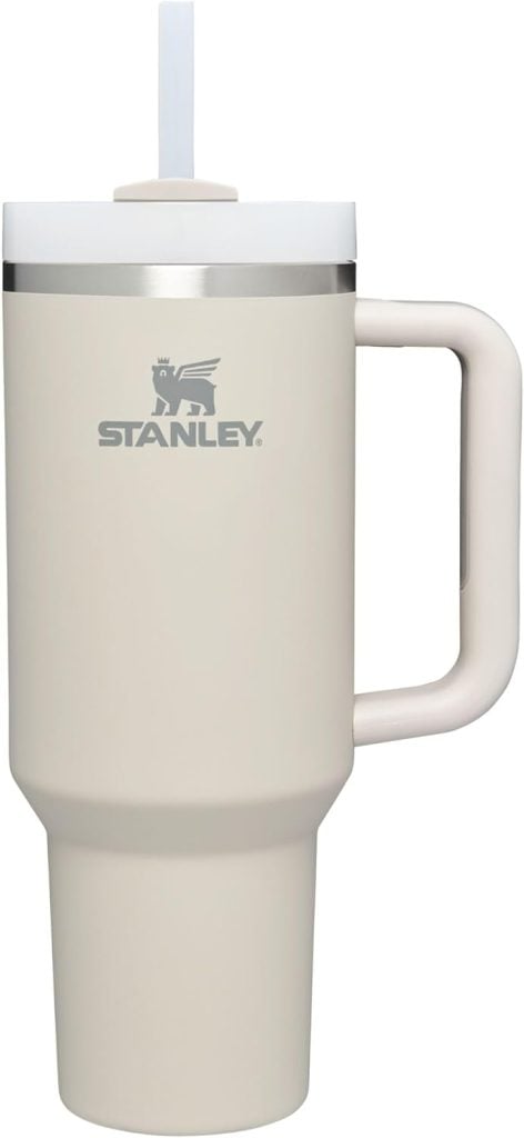 A beige Stanley travel mug, essential among kitchen items, features a convenient handle and a straw lid.