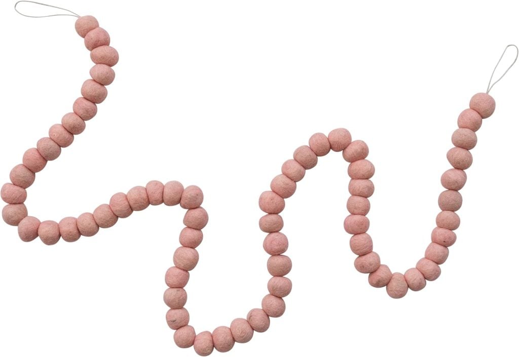 A string of round, pink air dry clay beads with loops at both ends, arranged in a wavy pattern on a white background.