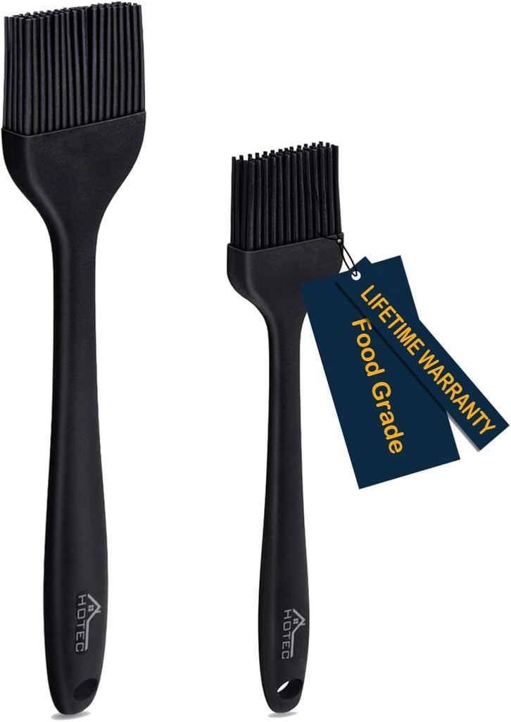 Two black silicone basting brushes, perfect for glazing your brown sugar bacon, come in two sizes: one larger and one smaller. With a tag reading "Lifetime Warranty, Food Grade," they're a must-have kitchen tool.