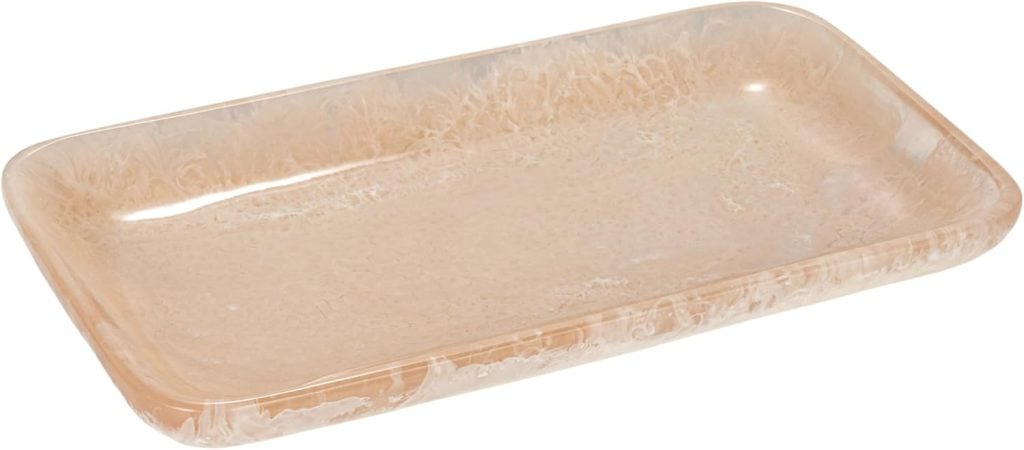 Rectangular beige tray with a marbled texture and smooth edges, viewed from an angle against a white background.