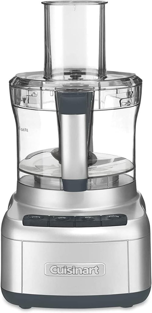 A silver Cuisinart food processor, a must-have among essential kitchen items, features a clear plastic bowl and black buttons on the base.