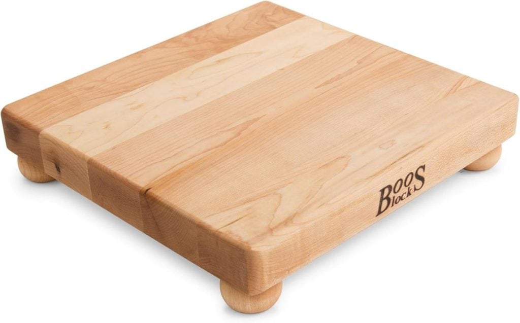 A square wooden cutting board with rounded corners and small round feet at each corner, branded with "Boos Blocks.