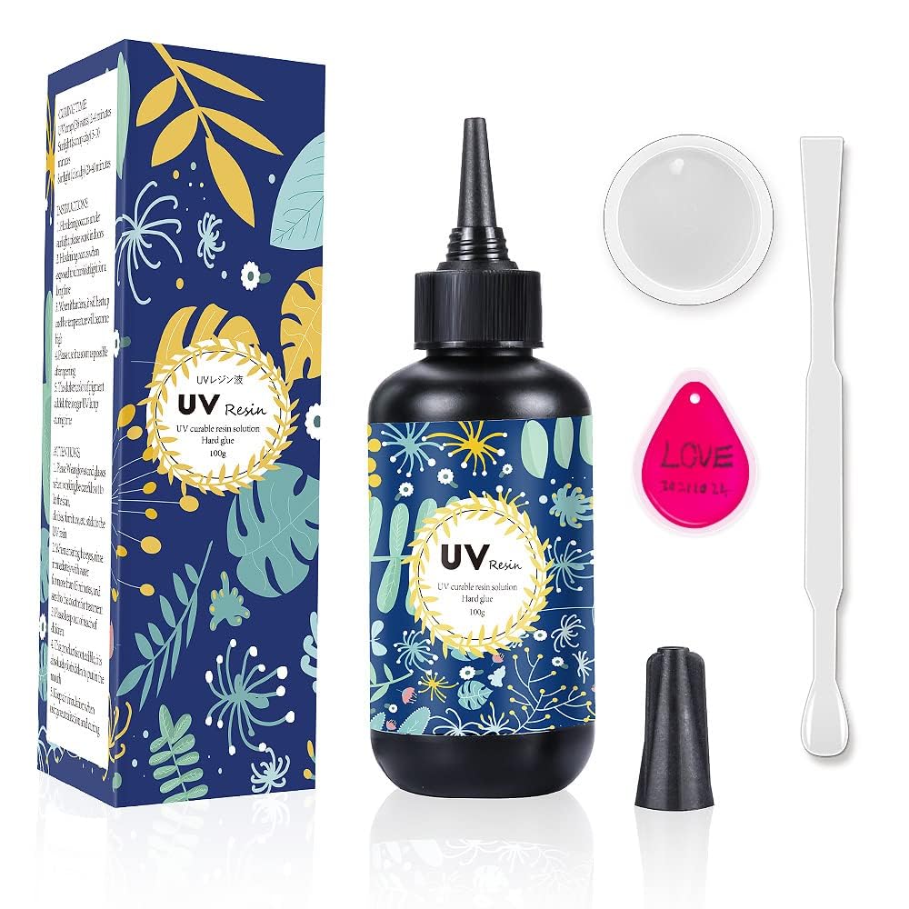 UV resin kit with a dark blue, flower-patterned bottle, nozzle cap, mixing stick, small container, and pink keychain tag. Box matches the bottle design.