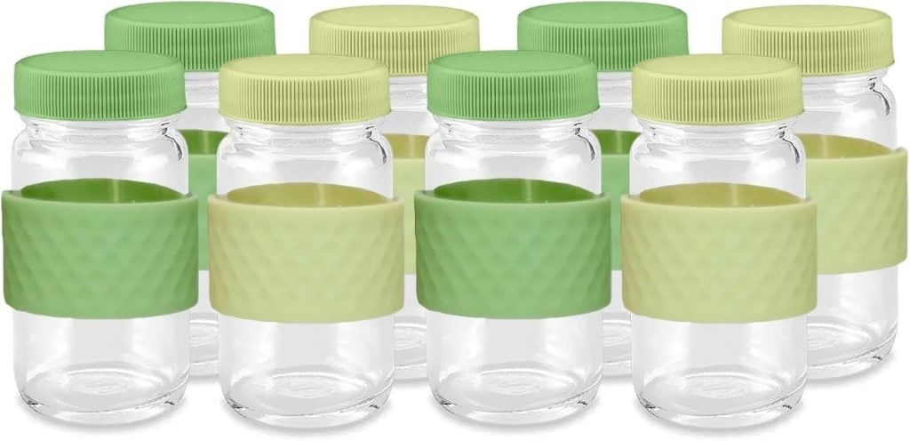 Eight small glass jars with green and yellow lids and silicone grips are arranged in rows.