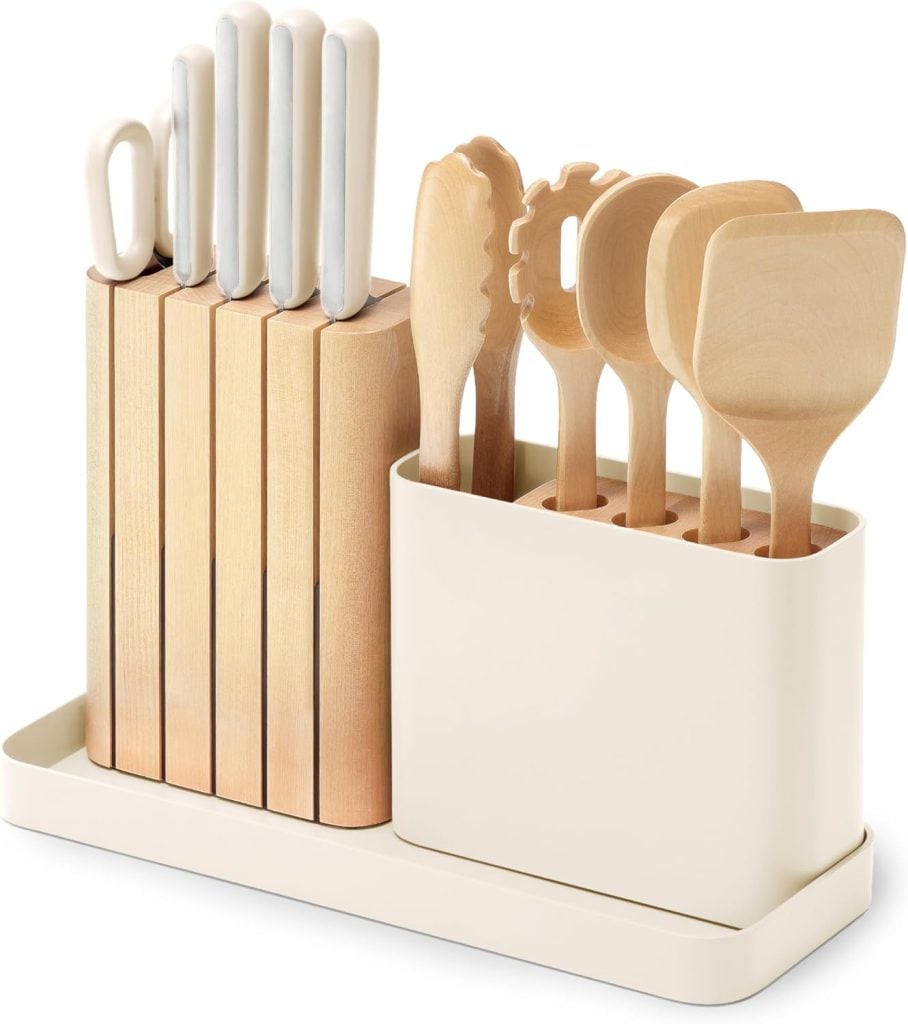 A set of kitchen knives and wooden utensils, among other kitchen items, are neatly organized in a cream-colored holder on a countertop.