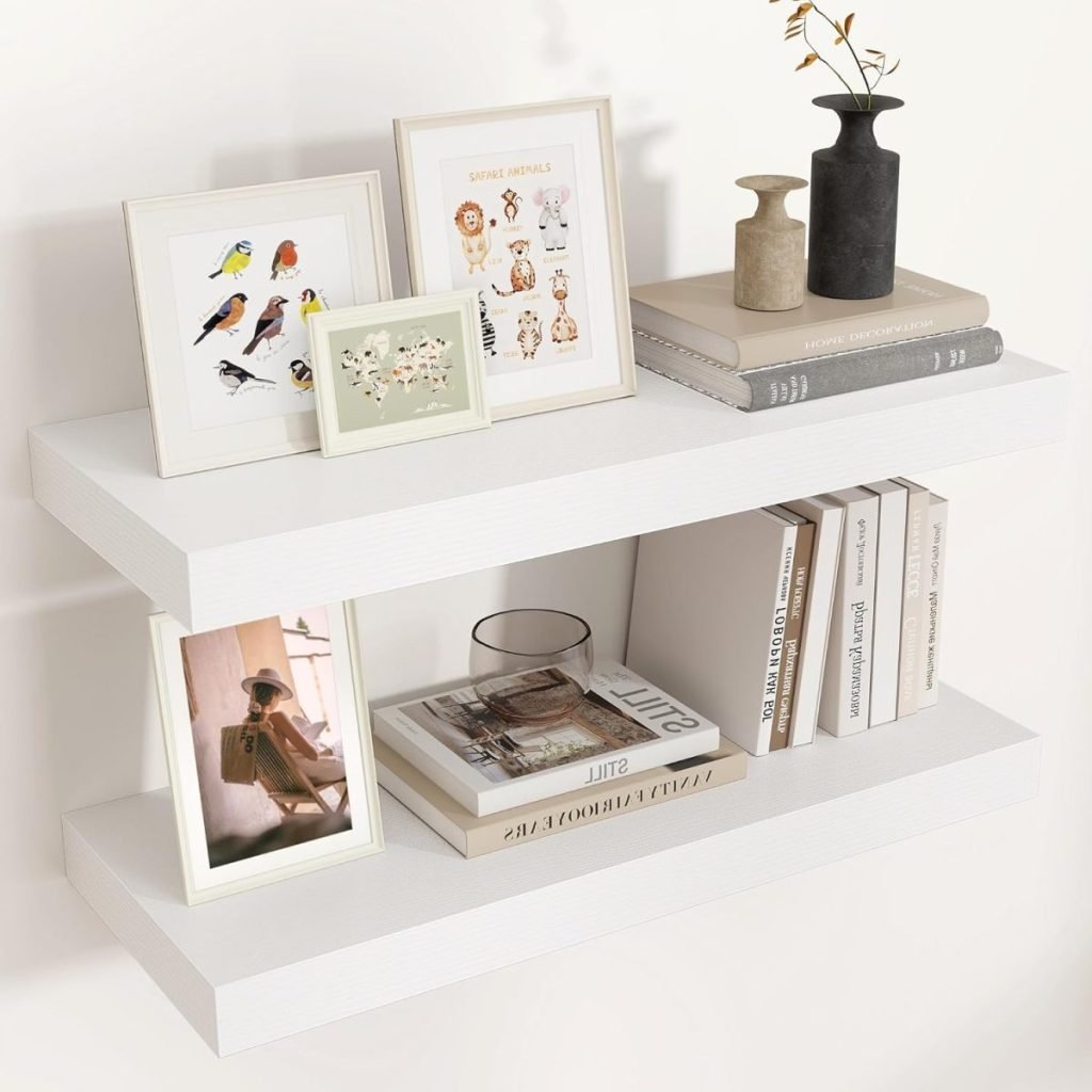 A white two-tier shelf in an open kitchen setting, adorned with framed animal illustrations, books, a small plant, and decorative vases.