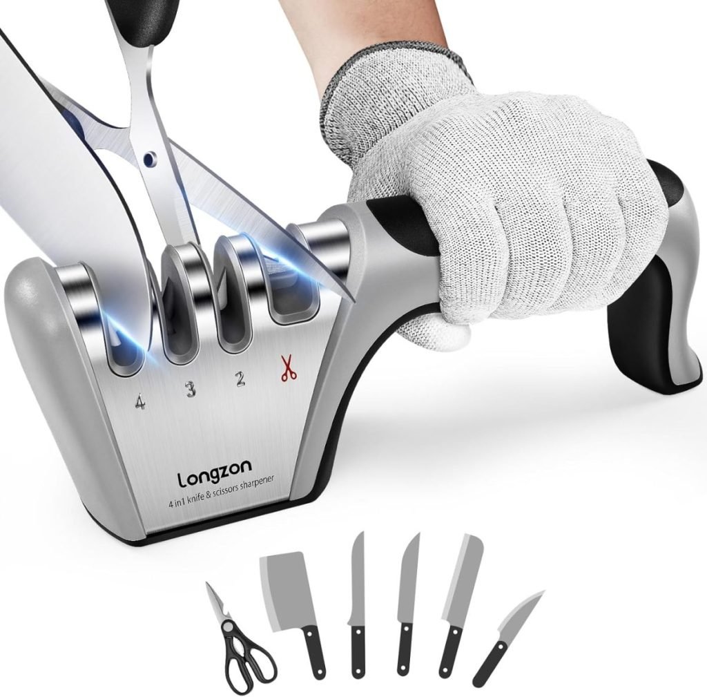 A hand in a glove expertly sharpens scissors with a 4-in-1 sharpener. Various kitchen items, including knives and a pair of scissors, are displayed below the sharpener.