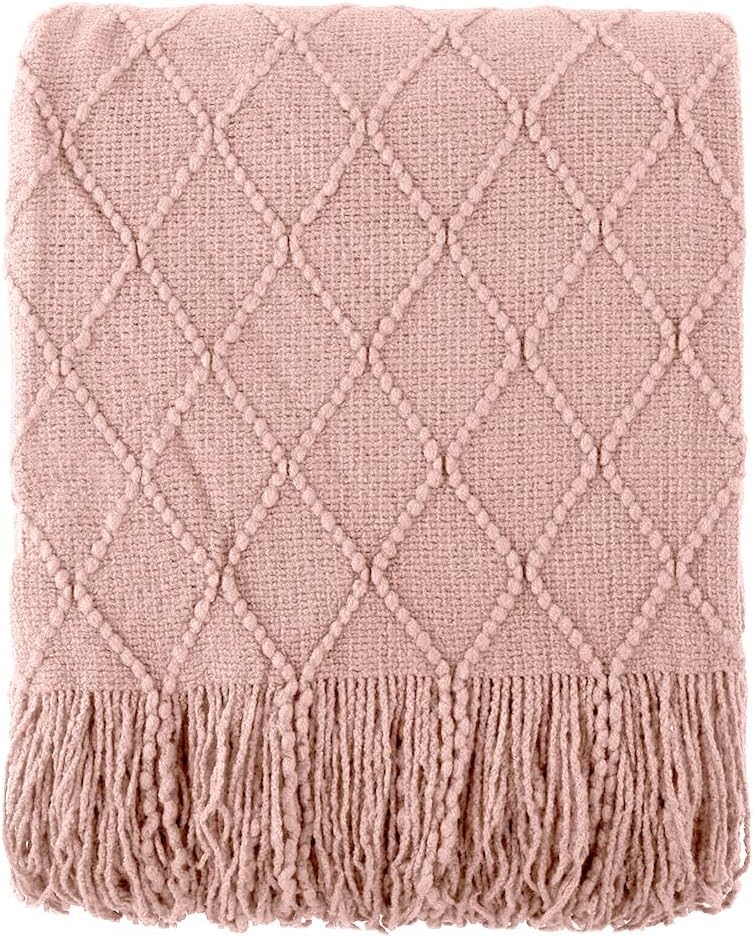 A folded, beige woven blanket with a diamond pattern and fringed edges.