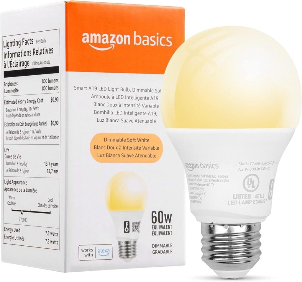 Amazon Basics 60W dimmable soft white LED light bulb in front of packaging, featuring compatibility with Alexa and energy-saving details.