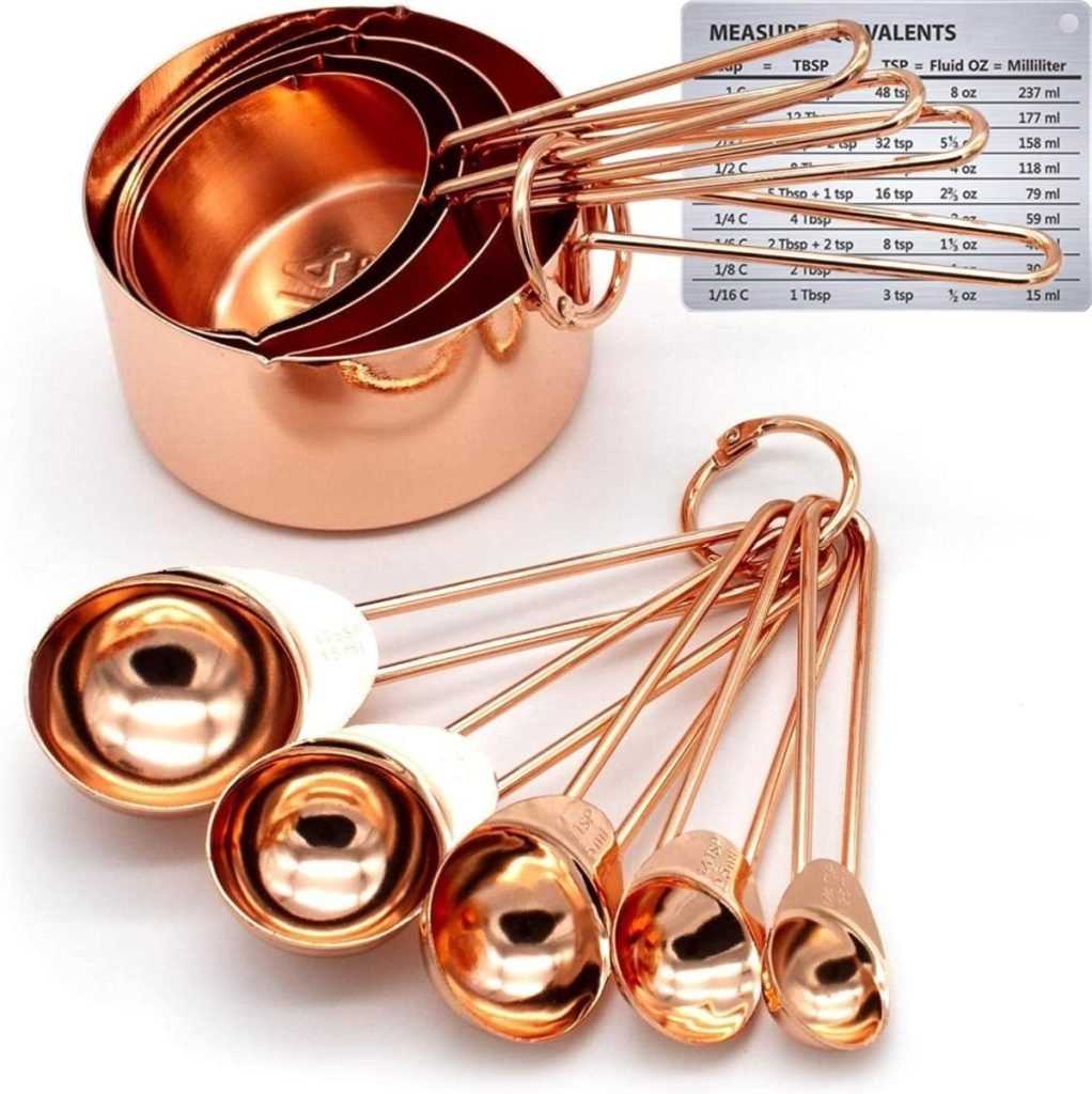 This elegant set of copper measuring cups and spoons, accompanied by a handy conversion chart in the background, is the perfect addition to your collection of essential kitchen items.