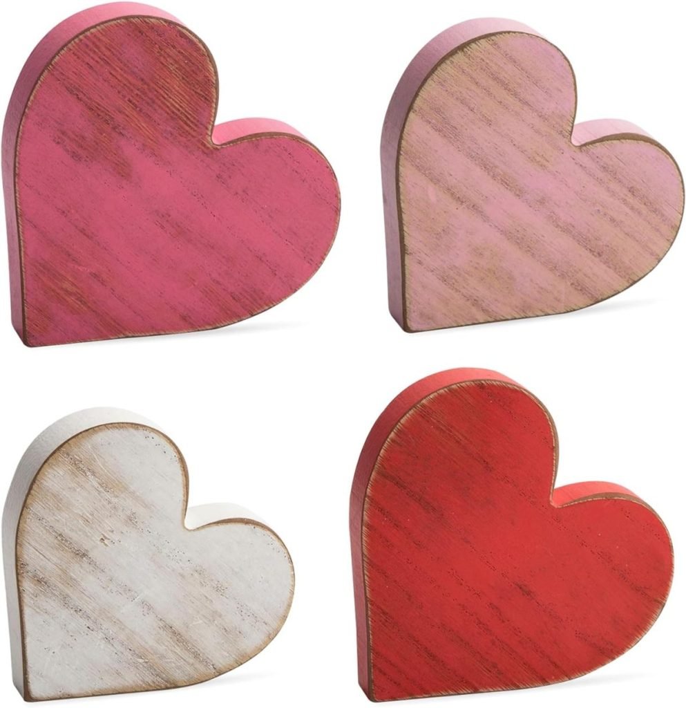 Four wooden heart shapes in pink, light pink, white, and red are arranged in a grid pattern.