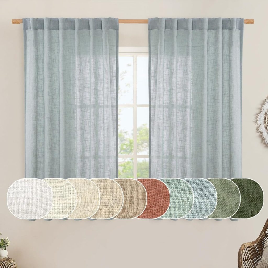 Light blue curtains hang on a wooden rod above a window. Below are fabric swatches in various colors, including beige, brown, blue, and green tones. A partial view of a framed mirror is on the right.