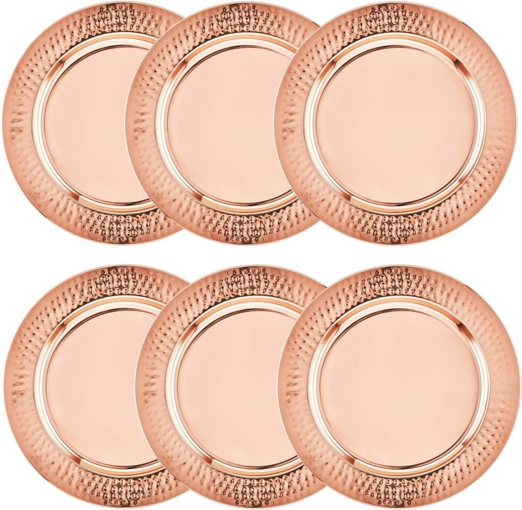 Six round, metallic rose gold plates with textured rims are arranged in two rows of three against a white background, their sheen reminiscent of valentine's hearts.