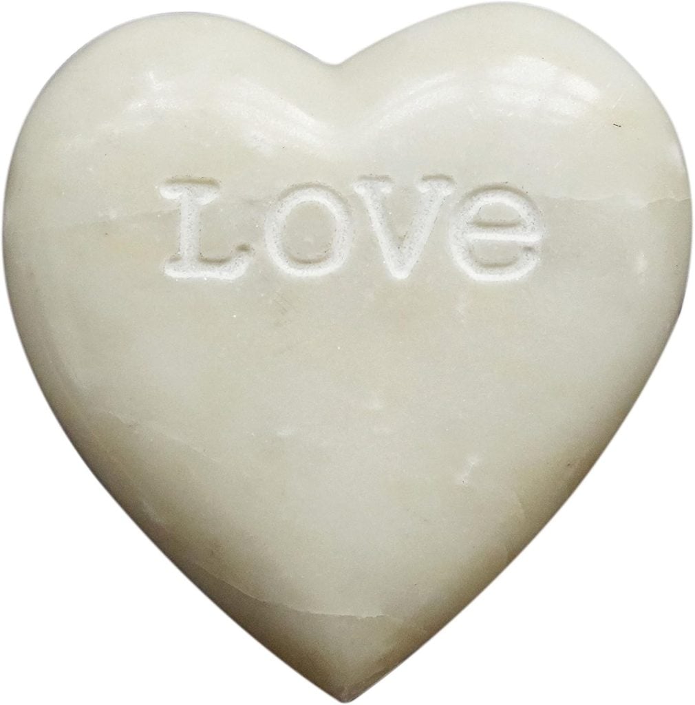 A white, heart-shaped stone crafted from air dry clay, with the word "LOVE" engraved in capital letters on its surface.
