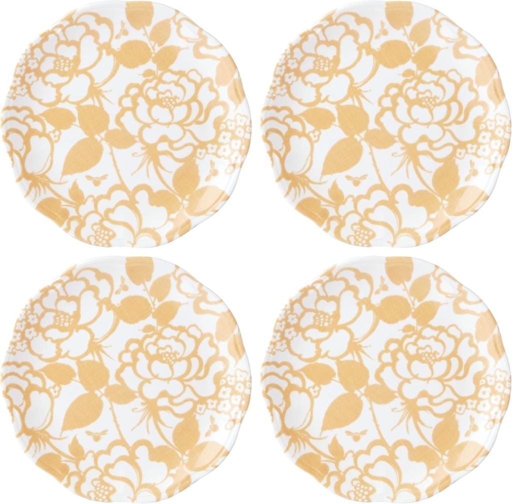 Four round plates with a yellow floral pattern and subtle valentine's hearts on a white background, arranged in a square formation.