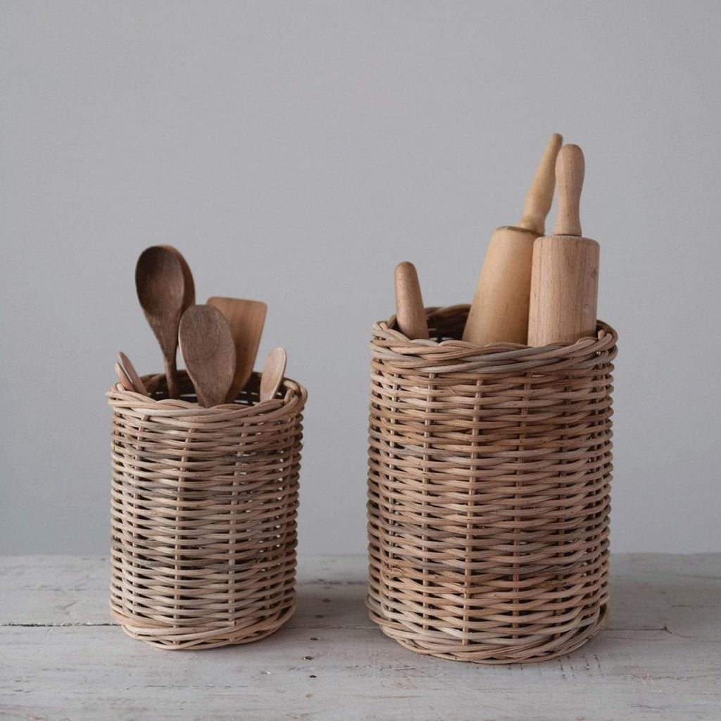 Two woven baskets on a white surface; one contains wooden spoons, the other holds rolling pins and utensils. The neutral tones evoke a cozy winter color palette against the plain gray background.