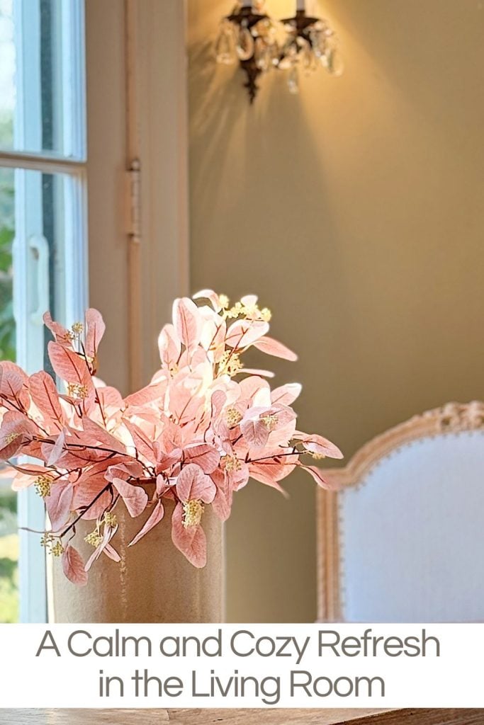 A vase with pink leaves on a table in a warmly lit living room.