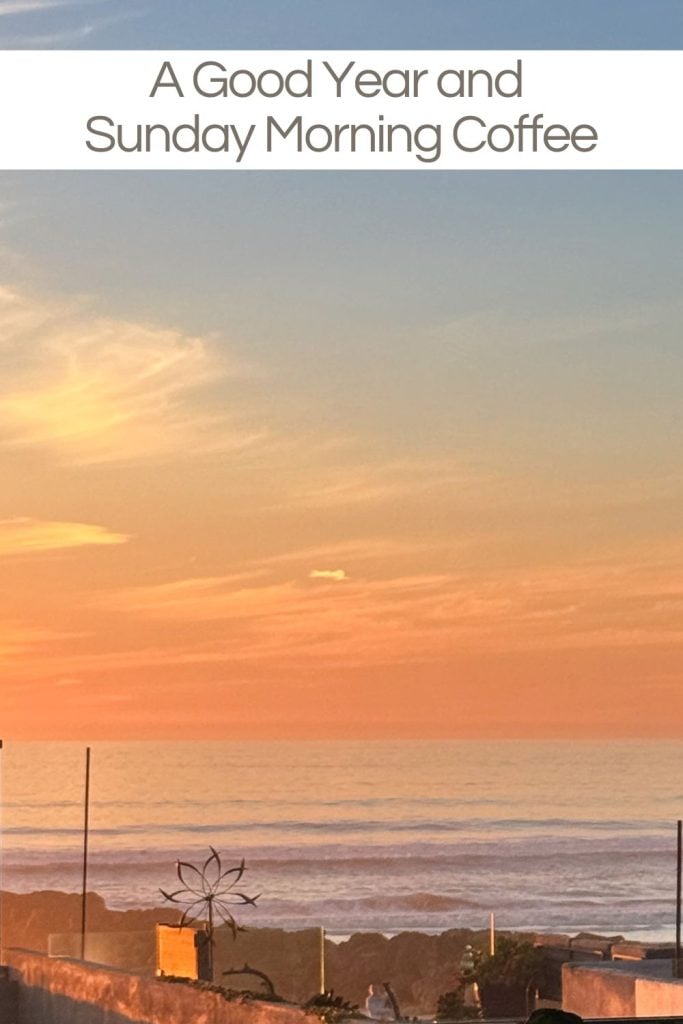 A calm ocean view at sunset with a colorful sky. A wind sculpture is visible in the foreground. Text at the top reads "A Good Year and Sunday Morning Coffee.