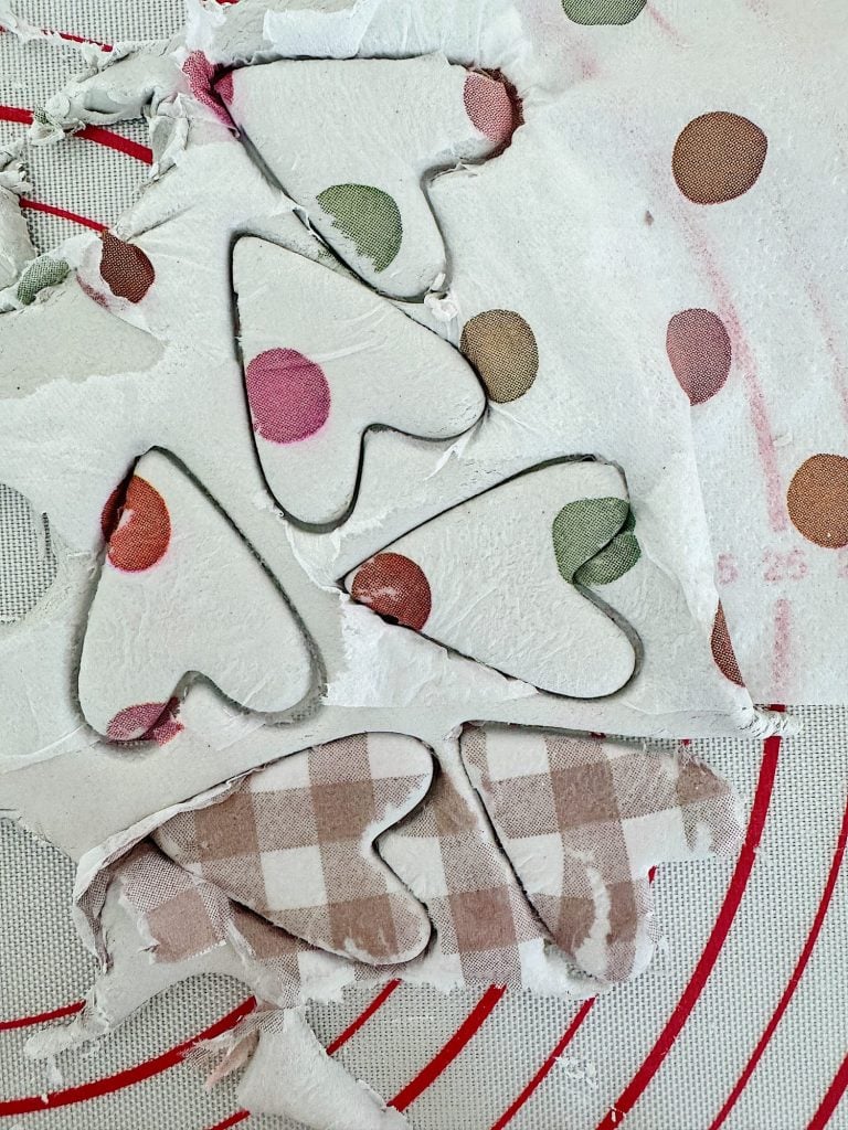 Heart shapes cut from fabric with polka dot and checkered patterns on a red and white mat.