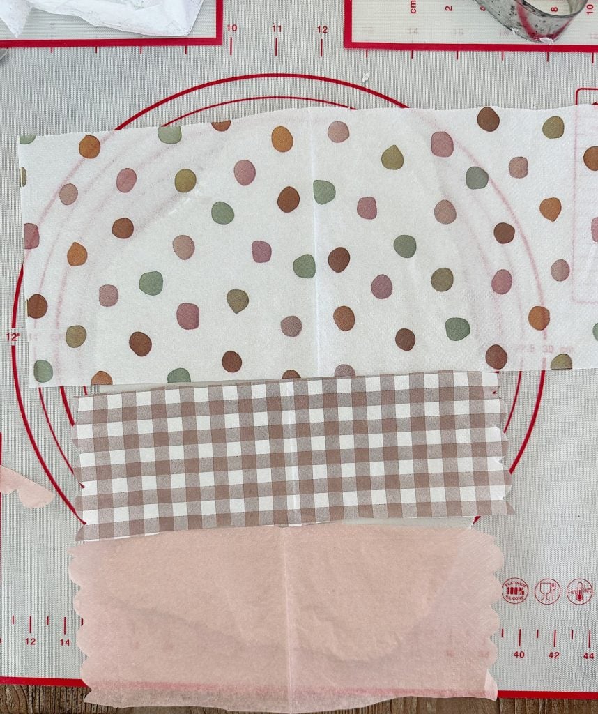 Three fabric swatches laid out on a measuring mat: a polka dot pattern, a gingham pattern, and a plain pink fabric.