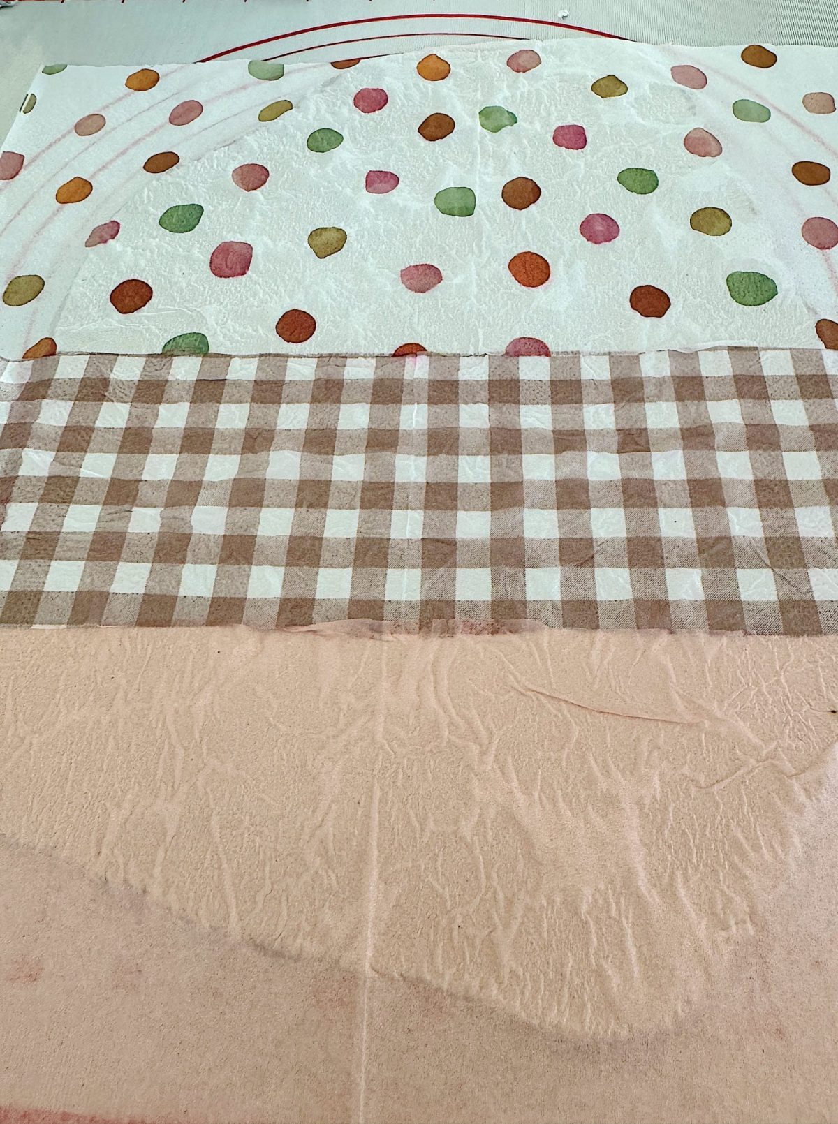 Colorful polka dot pattern on top, brown checkered pattern in the middle, and plain beige fabric at the bottom, all laid out flat.