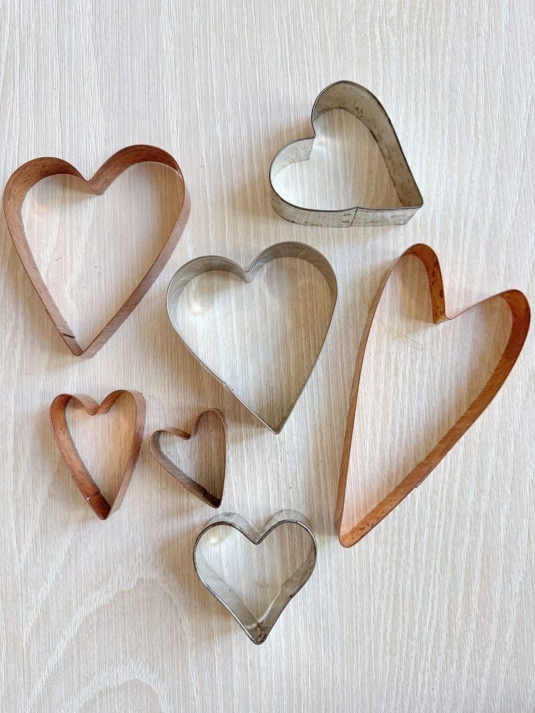 Seven heart-shaped cookie cutters of varying sizes arranged on a wooden surface.