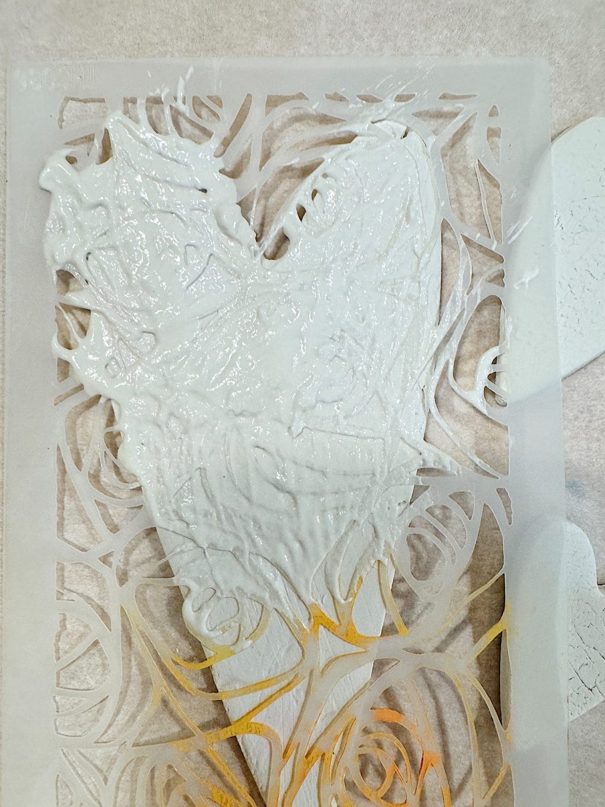 A textured white heart shape with swirling patterns on transparent paper, laid on a flat surface.