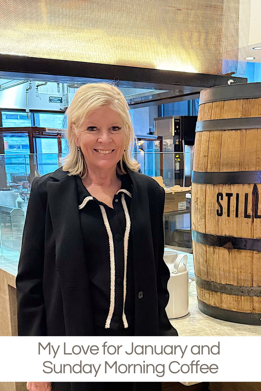 A person with blonde hair in a black outfit stands indoors near a large wooden barrel with "STILL" written on it.