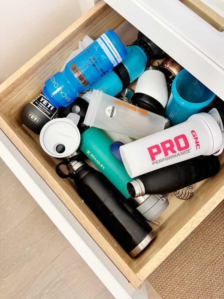 A drawer filled with various water bottles, including brands like YETI and GNC Pro Performance, in assorted colors and designs.