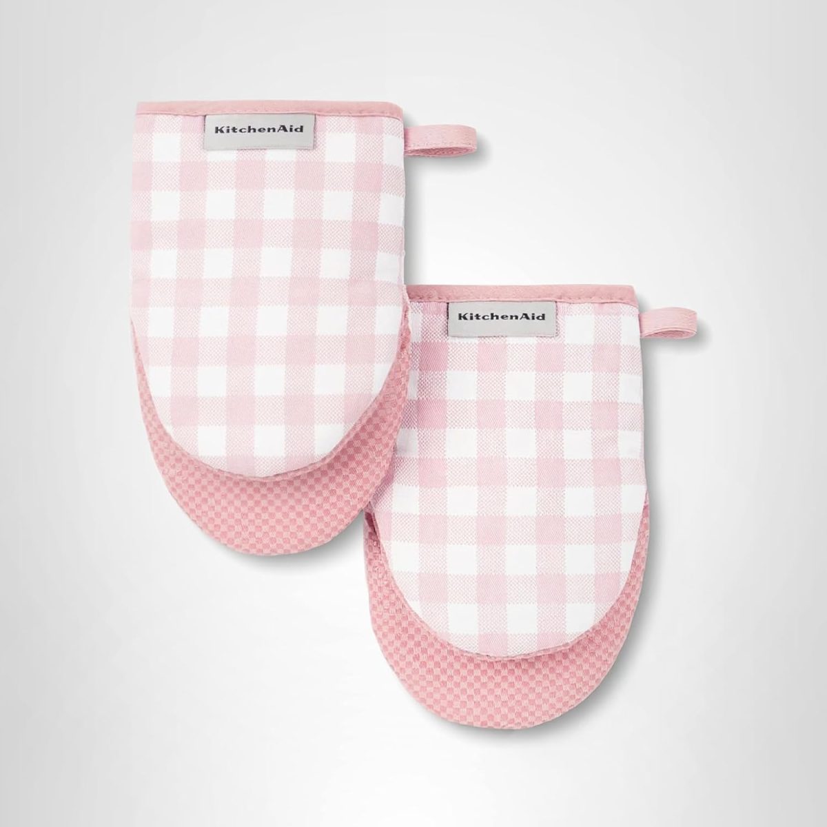 Two pink and white checkered KitchenAid oven mitts with loops for hanging are displayed on a plain background&mdash;perfect for your next Valentine DIY project.