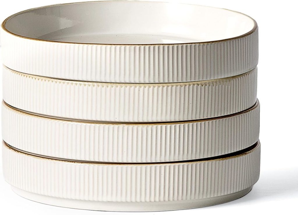 A stack of four white, round, ribbed ceramic bowls with a subtle gold rim, perfect for serving dishes like baked parmesan crusted chicken, set against a plain background.