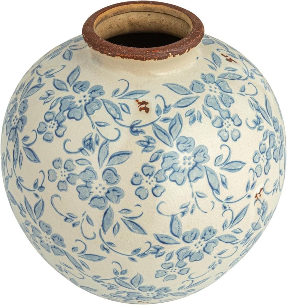 A round ceramic vase with a wide opening, decorated with blue floral patterns on a white background and some visible brown spots&mdash;perfect for displaying your best faux flowers.