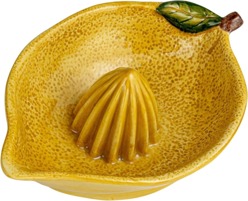 A yellow ceramic lemon-shaped citrus juicer with a textured surface and a green leaf detail on the rim&mdash;perfect for squeezing fresh juice for your favorite cream pie recipes.