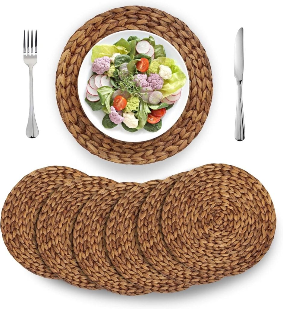 A plate of salad is placed on a round woven placemat, with a fork on the left, a knife on the right, and five additional woven placemats below—perfect for inspiring your dining room table decor.