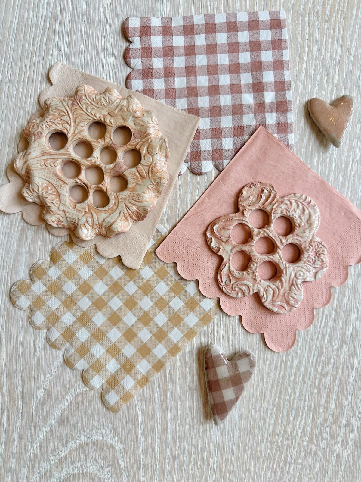 Patterned napkins, flower frogs with hole designs, and heart-shaped items are arranged on a light wooden surface.