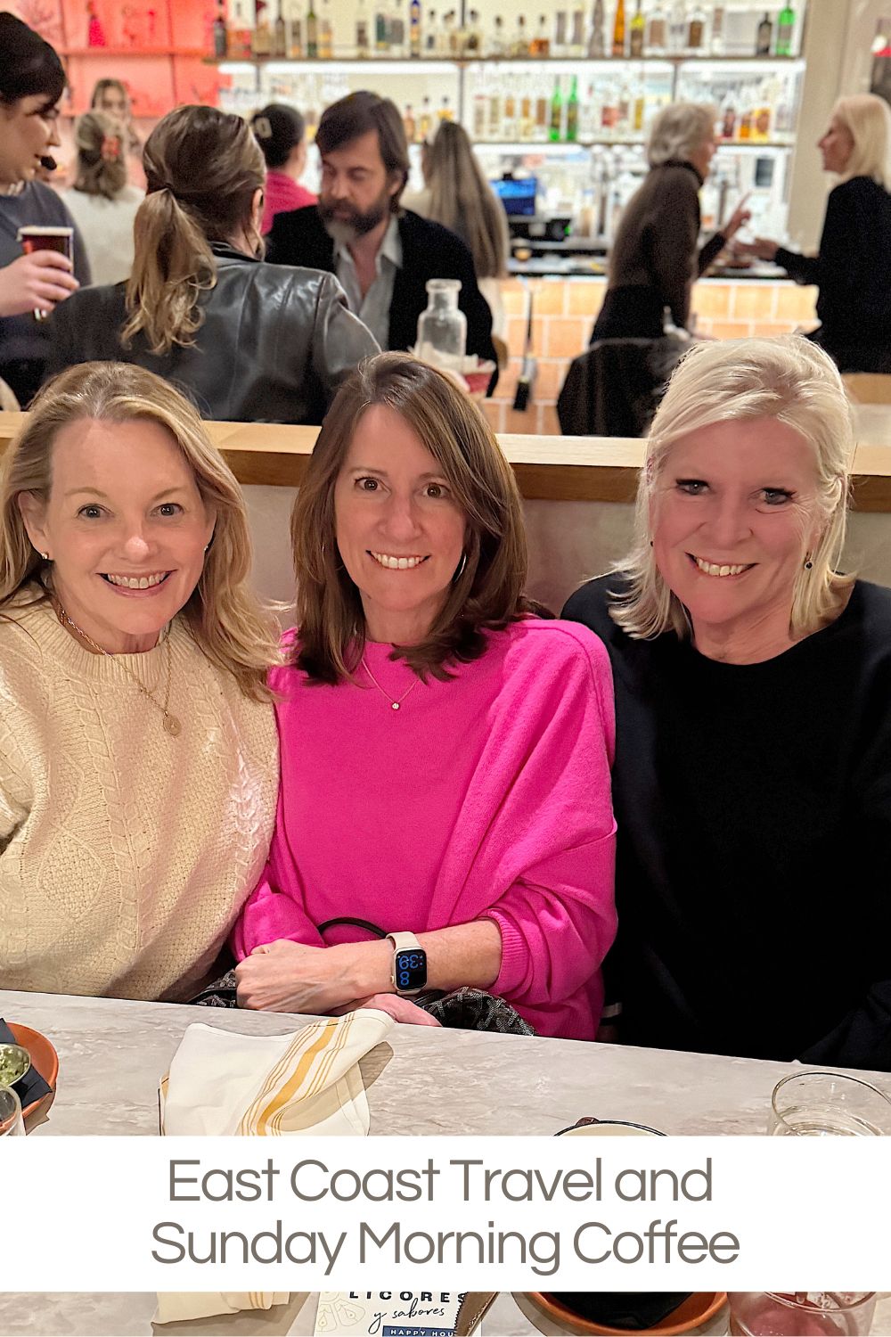 Three women sitting together at a table in a bustling cafe.