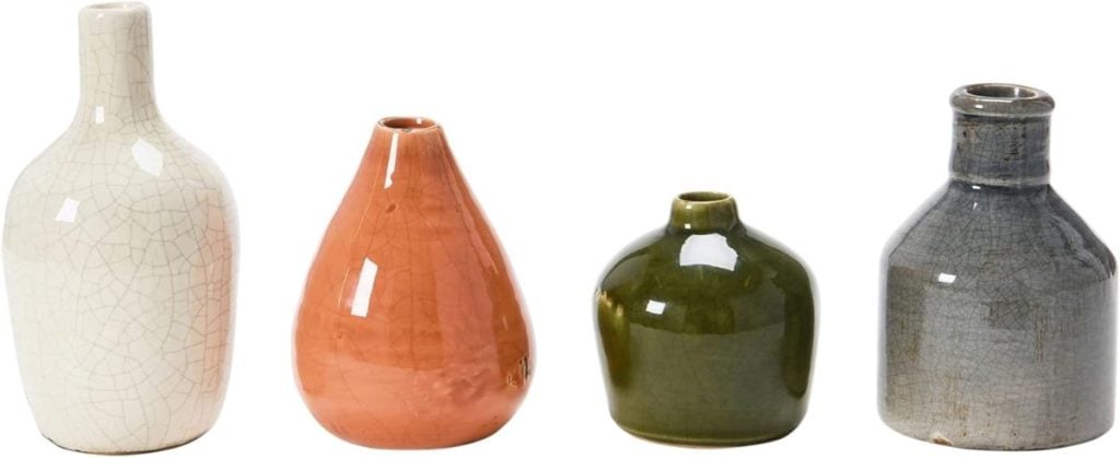 Four small ceramic vases in different shapes and colors—white, orange, green, and gray—arranged in a row on a white background, perfect for adding a fresh touch to your spring decor.