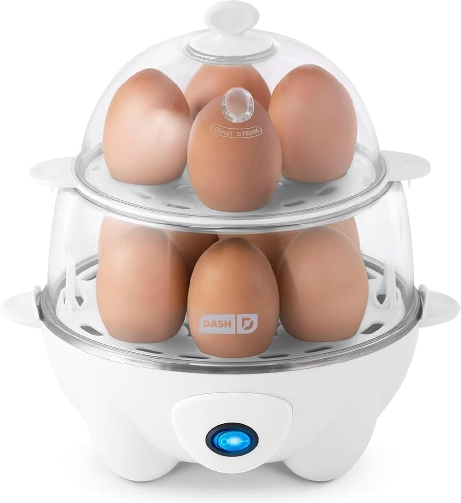 A two-tier electric egg cooker with a clear lid holds ten brown eggs and features a blue power indicator light on the front&mdash;perfect for making the Best Deviled Eggs Recipe every time.