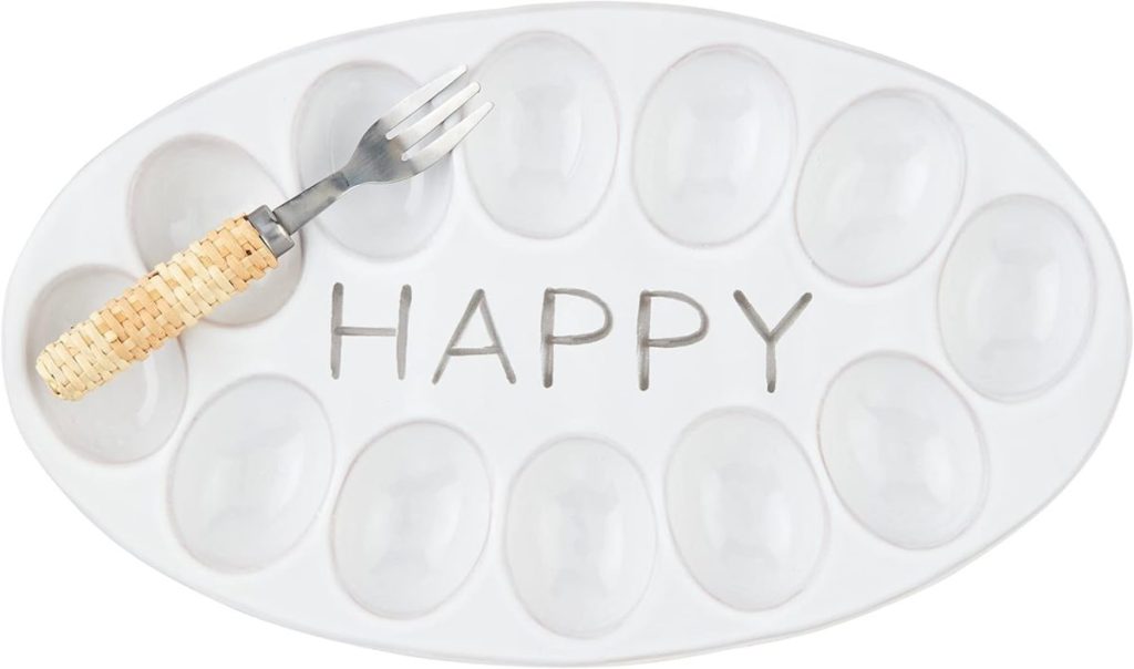 An oval white ceramic tray with twelve egg-shaped indentations, the word "HAPPY" in the center, and a small fork with a woven handle resting on it&mdash;perfect for displaying or serving plastic Easter eggs.