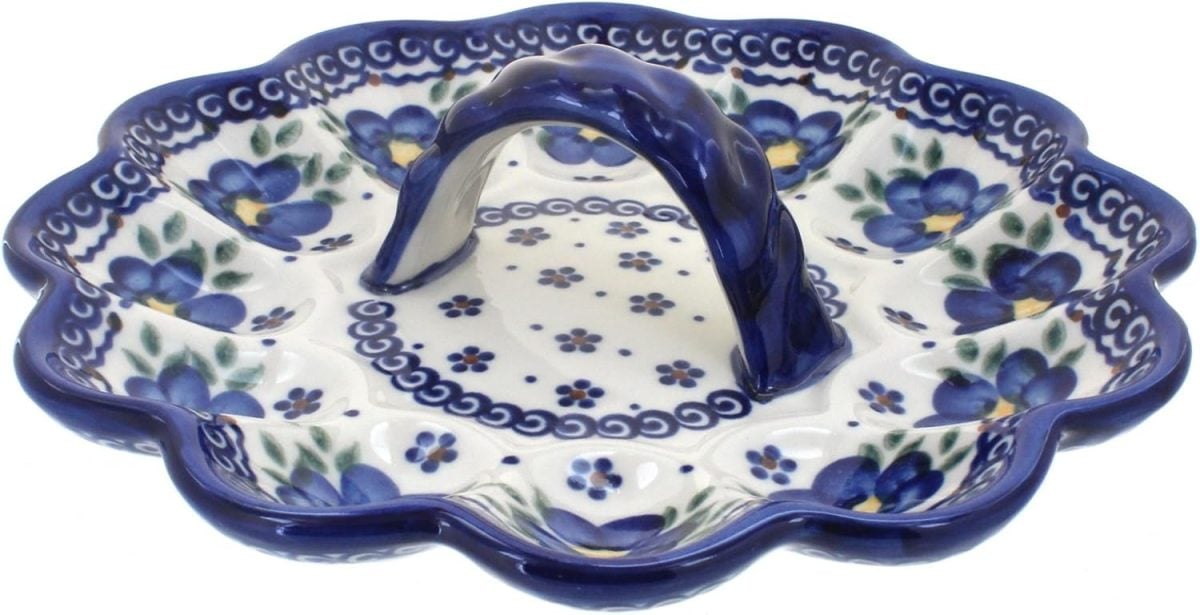 A scalloped ceramic serving dish with a central handle, decorated with blue and purple floral patterns and green leaves&mdash;perfect for showcasing your best deviled eggs recipe at any gathering.