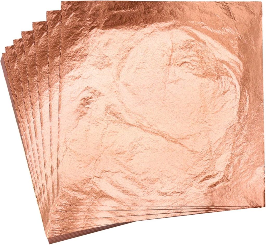 A stack of thin, metallic rose gold sheets with a smooth and crinkled texture, fanned out on a flat surface—perfect for adding a chic touch to your spring decor.