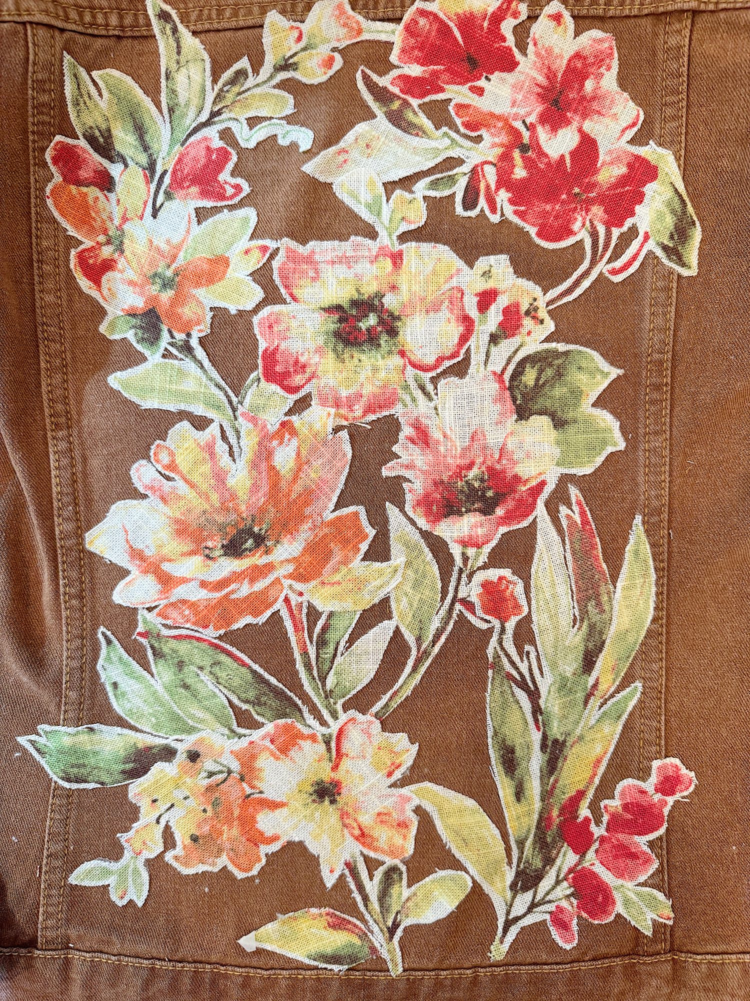 Floral pattern with red, orange, and yellow flowers on a brown fabric background.