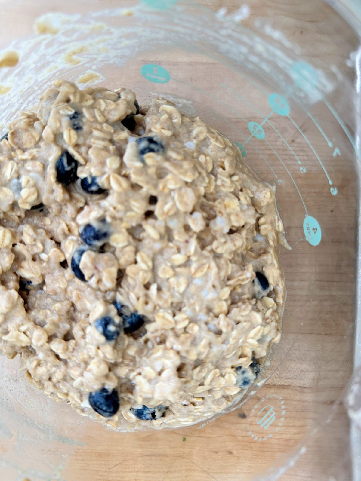 Bowl of oatmeal mixed with blueberries on a wooden surface.