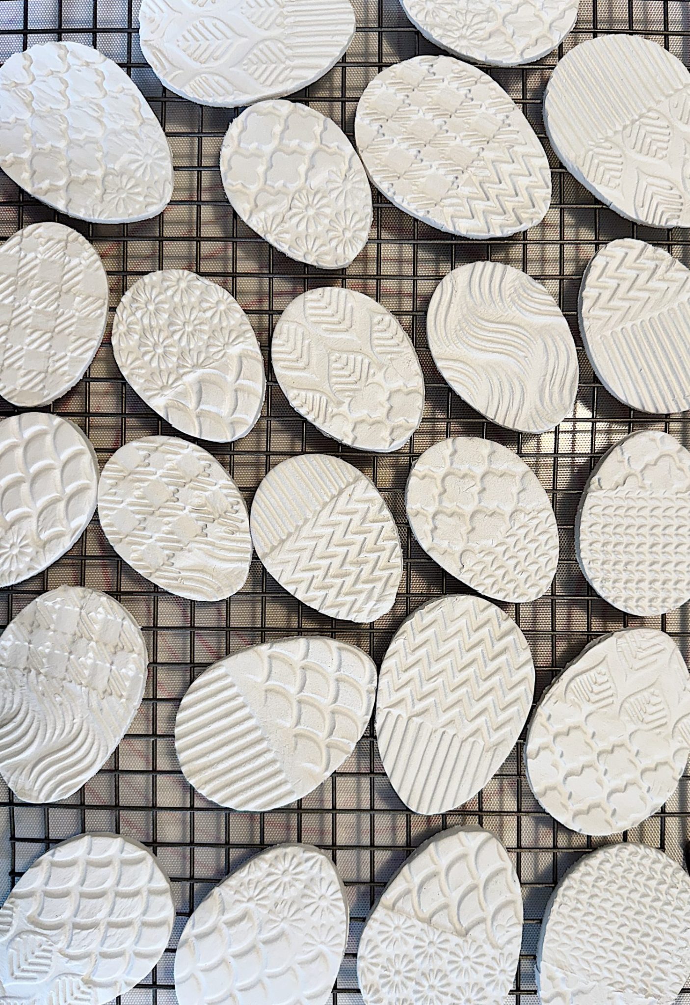 A grid displaying oval-shaped white ceramic pieces, each with a unique embossed pattern.