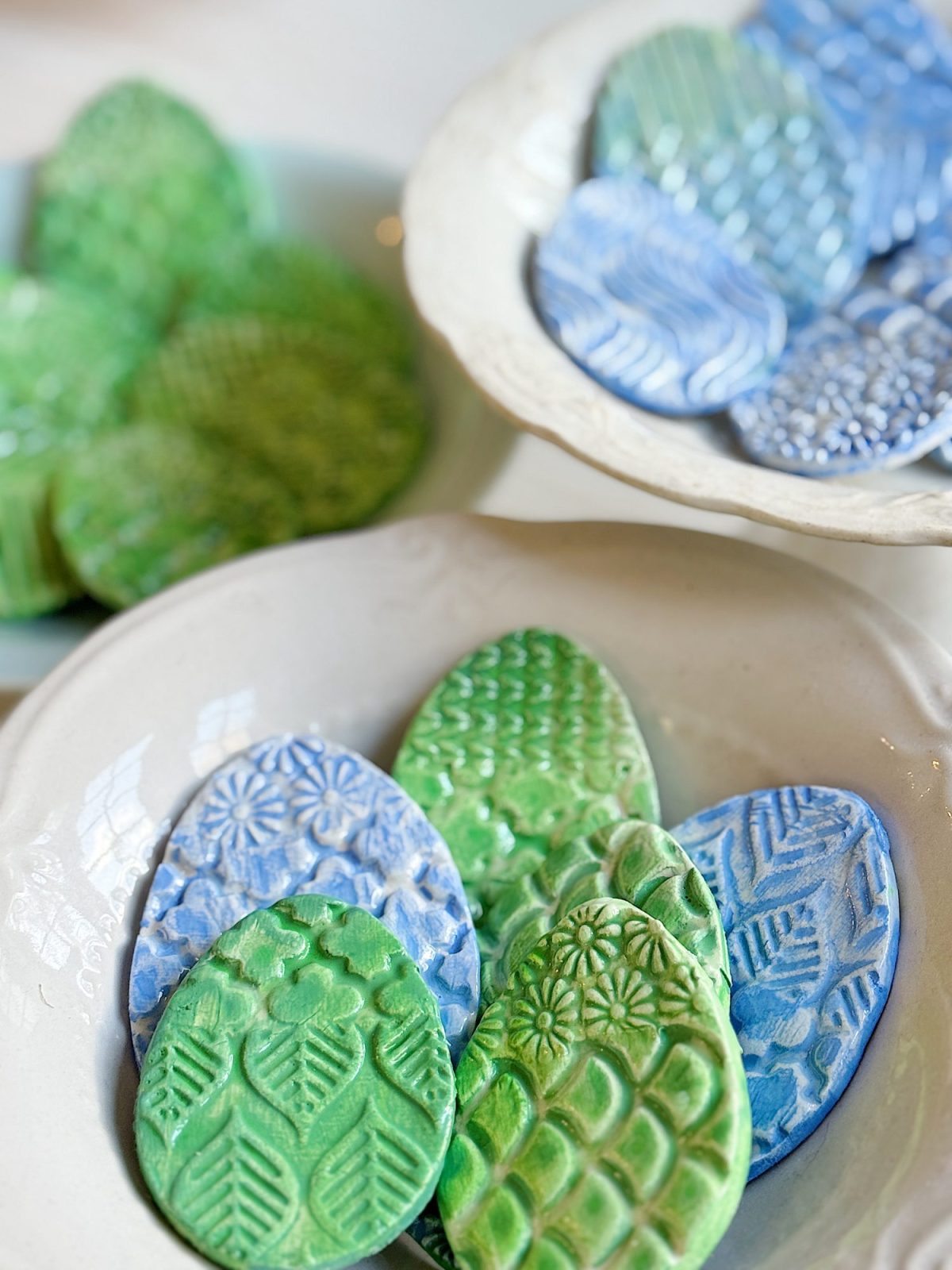 Bowls containing ceramic pieces shaped like eggs with textured patterns, in shades of blue and green.