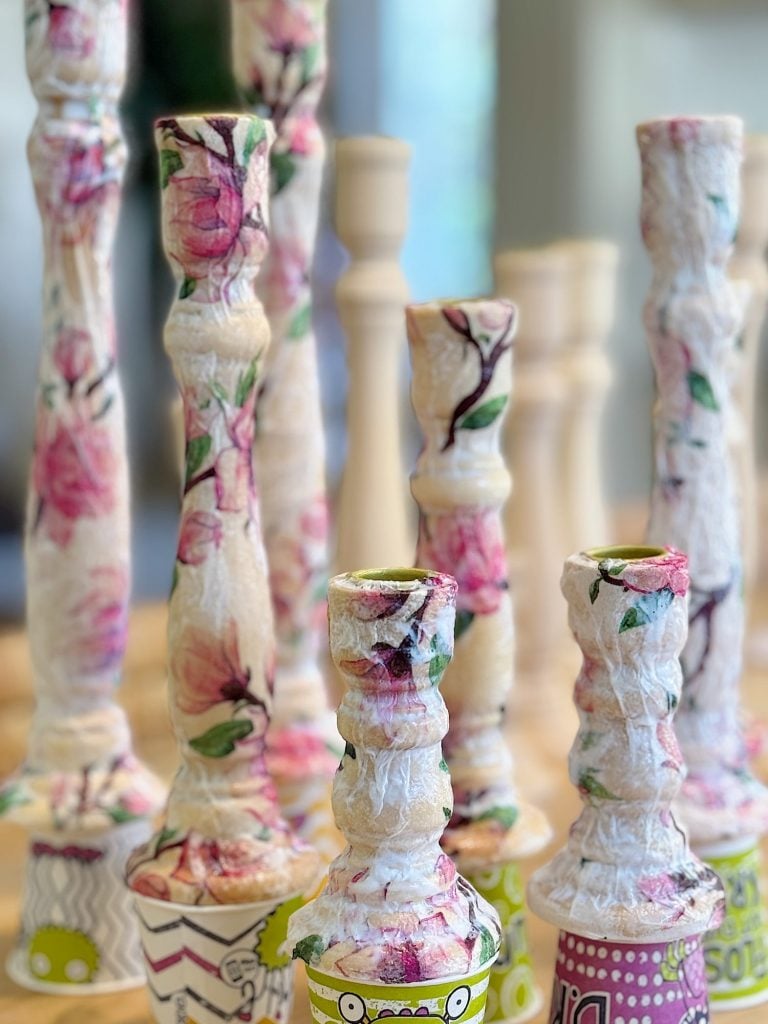 Decorative candlesticks with floral patterns and textured surfaces displayed upright on a table.