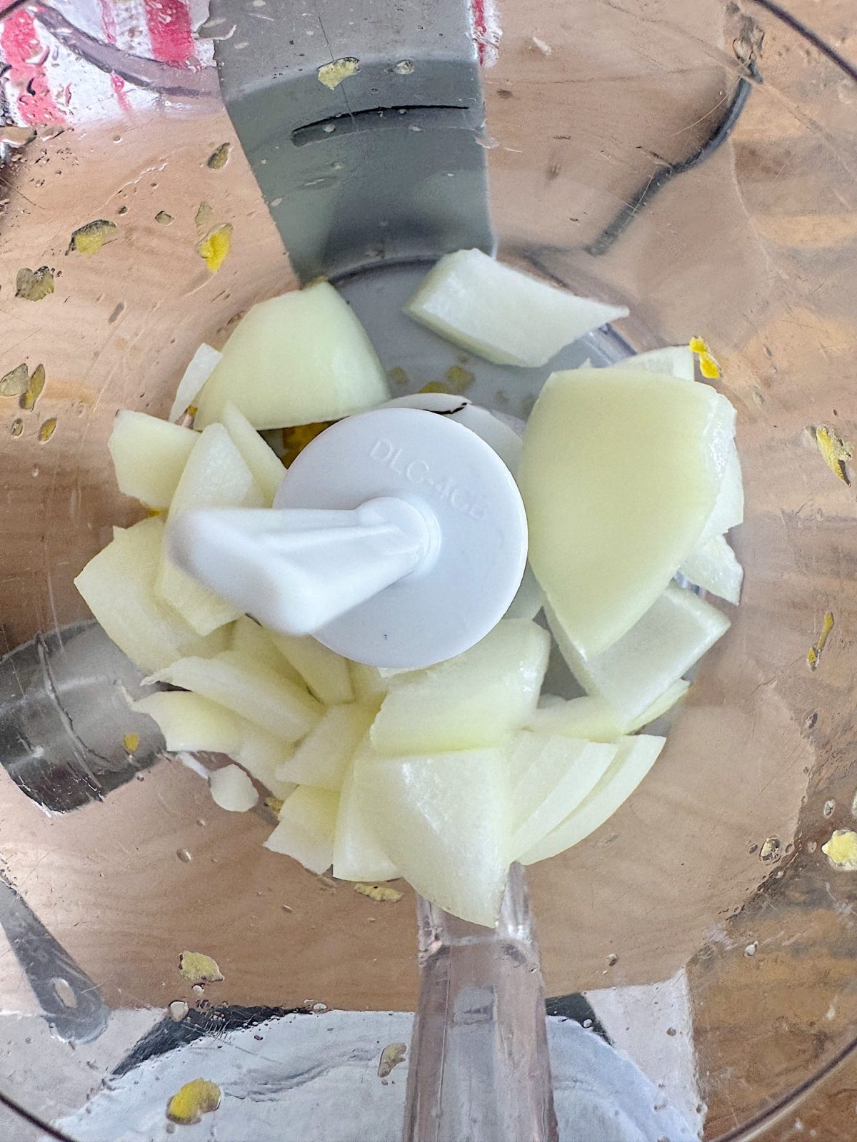 Chopped white onions in a food processor bowl with white plastic blade.