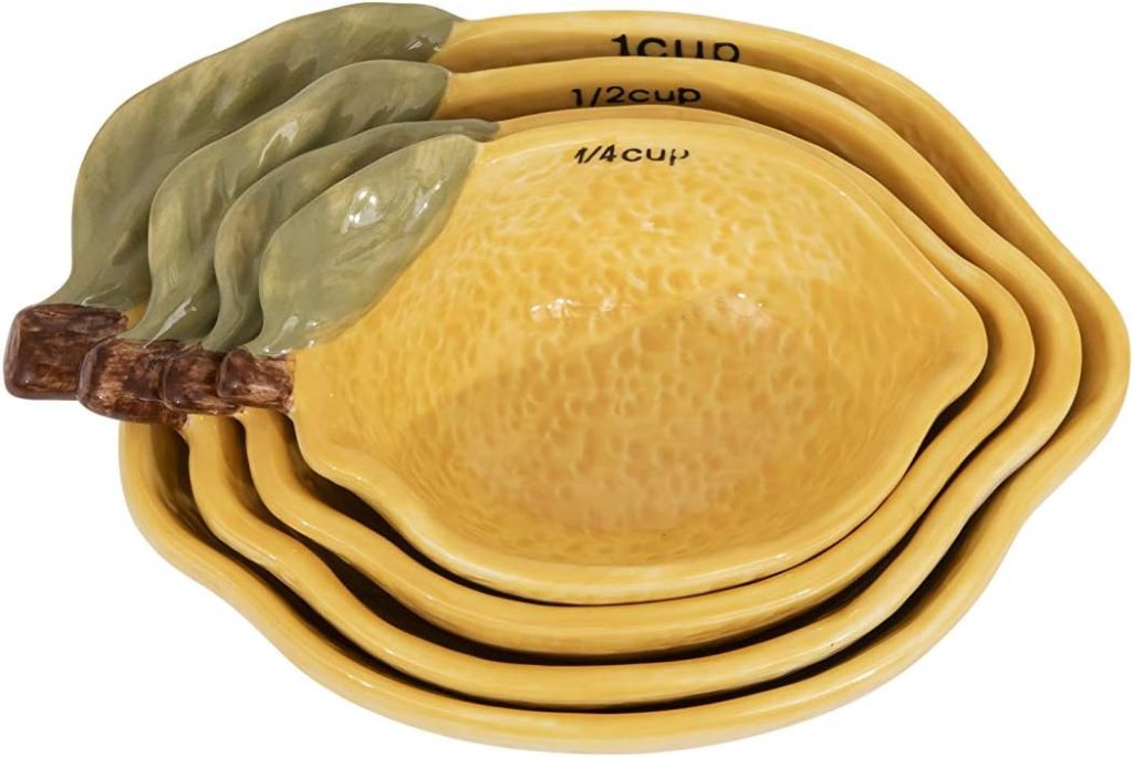 Four yellow ceramic measuring cups shaped like lemons, nested together with green leaf handles and measurement labels inside each cup&mdash;perfect for measuring out ingredients for your favorite lemon vodka recipes.